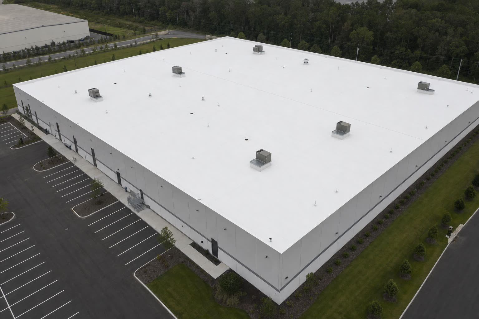 Aerial view of a white TPO warehouse roof with rooftop units and clean seams